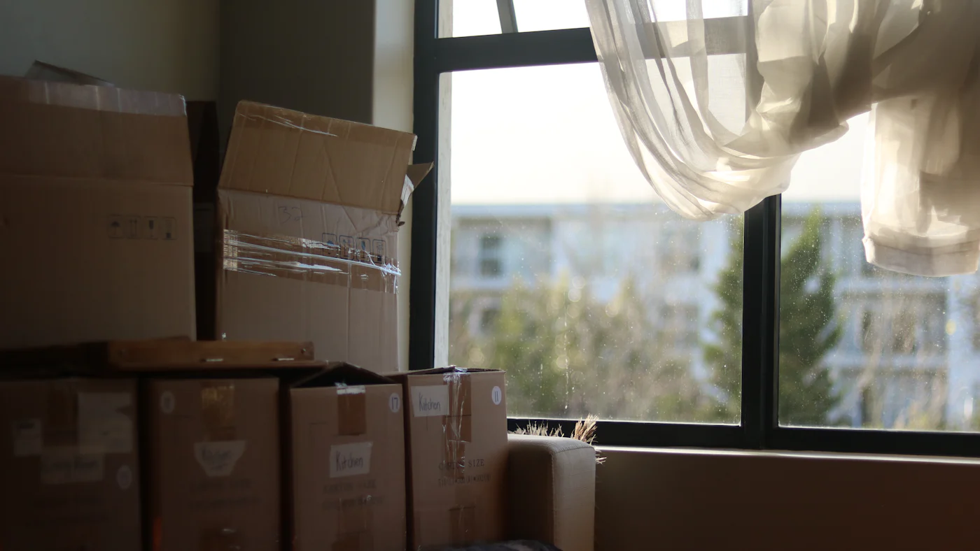An empty room with moving boxes beside a window