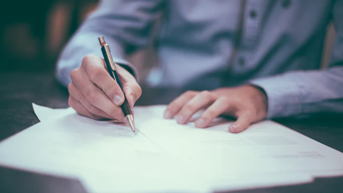 Someone writing notes on a document at a table