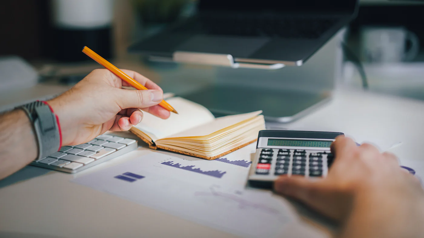 A desk with a calculator and a notebook