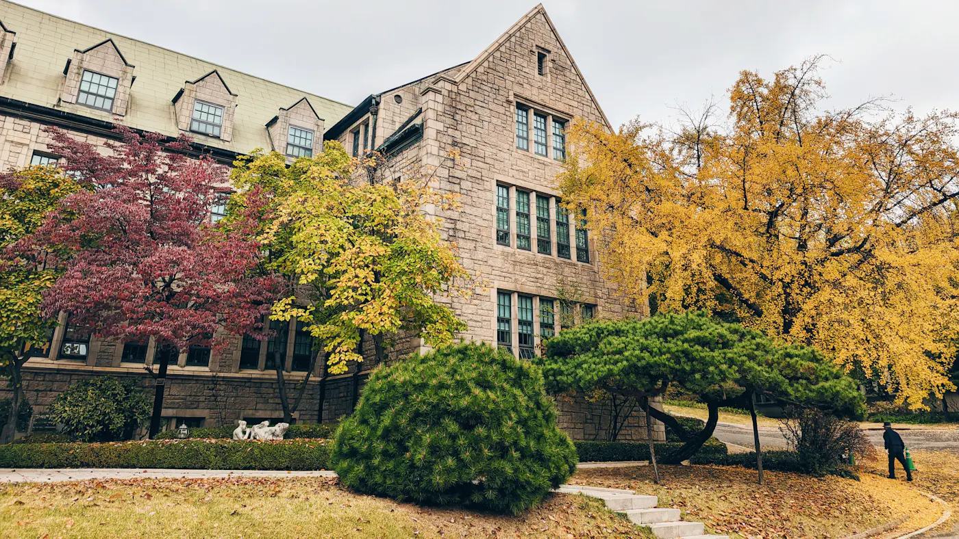 A large brick residence building behind trees
