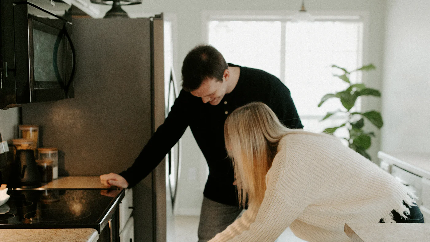 Two housemates cooking together at an oven
